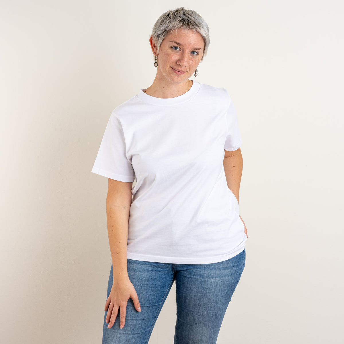 Front view of a woman in Gordina’s relaxed white T-shirt, with the burgundy Water and Garden embroidery positioned on the back. Made in the Netherlands.