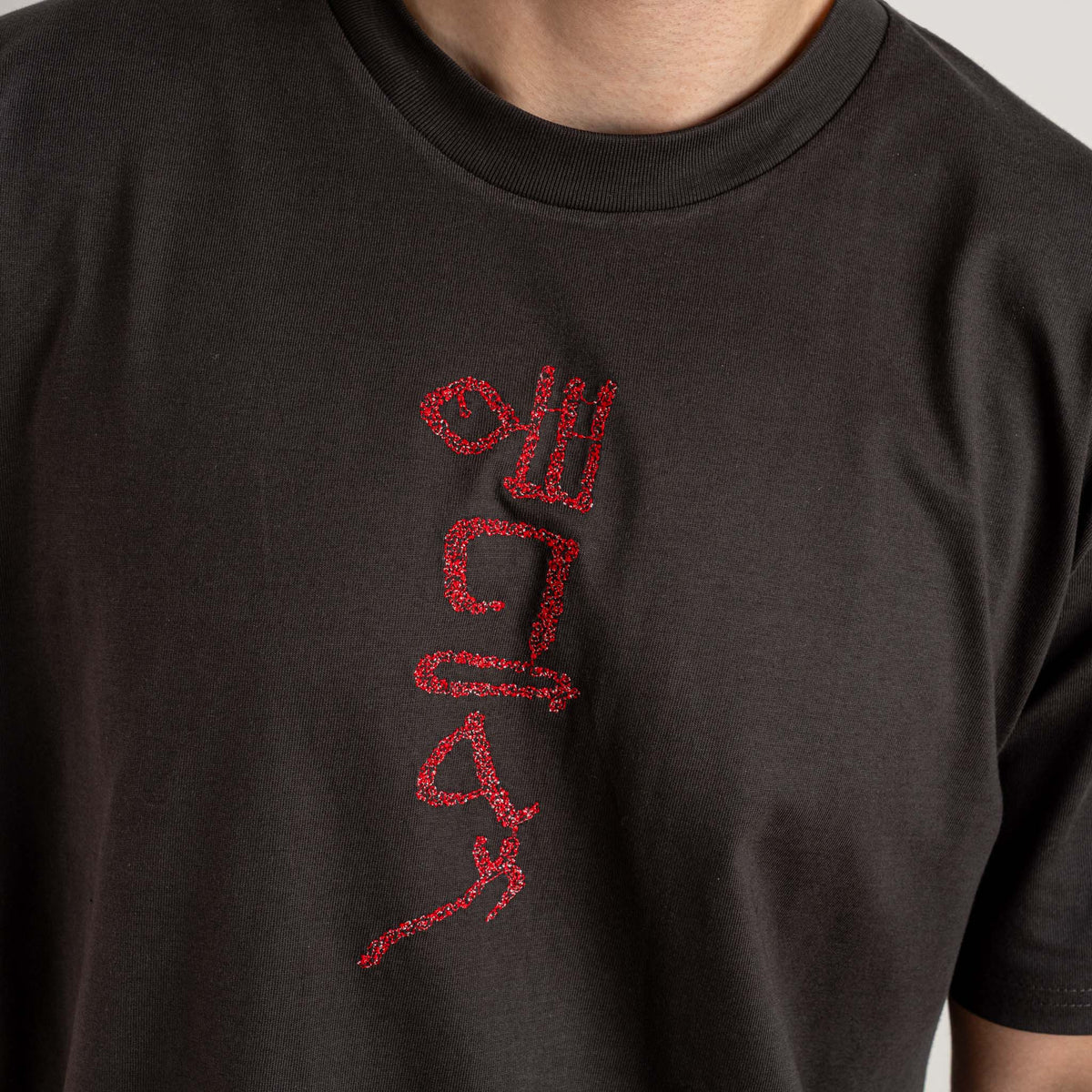 Close-up of the red embroidery on the Papyrus coal T-shirt