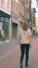 Woman walking down a Utrecht street in a bone GORDINA T-shirt with a balck embroidered folk figure on the back