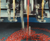 Embroidery machine needles stitching a red scarab motif in the Gordina studio