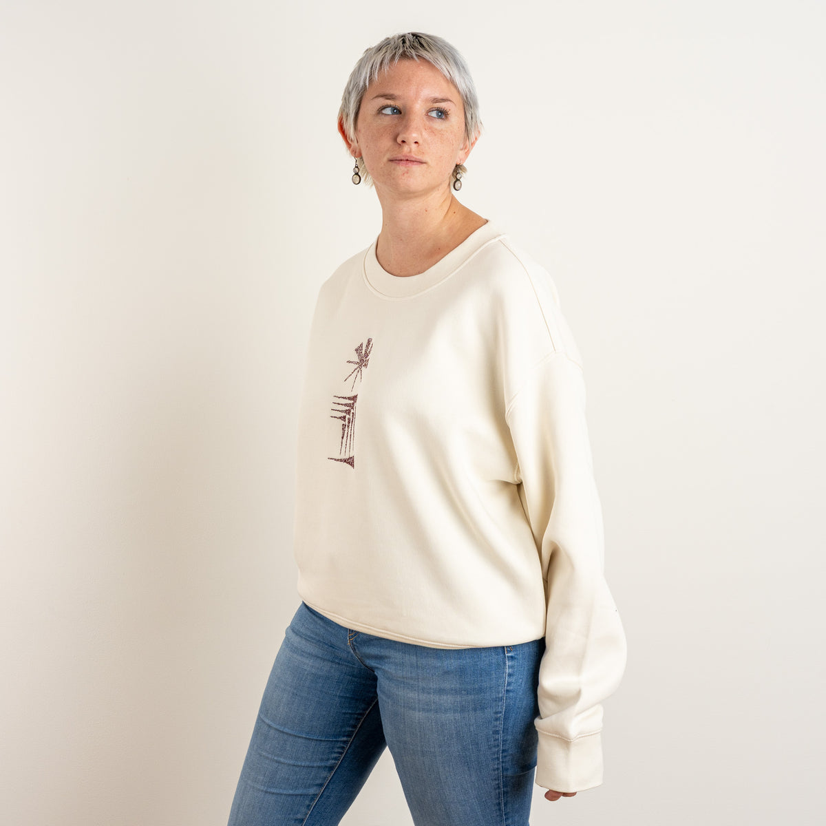 Profile view of the ecru Star and House embroidered sweatshirt on a model