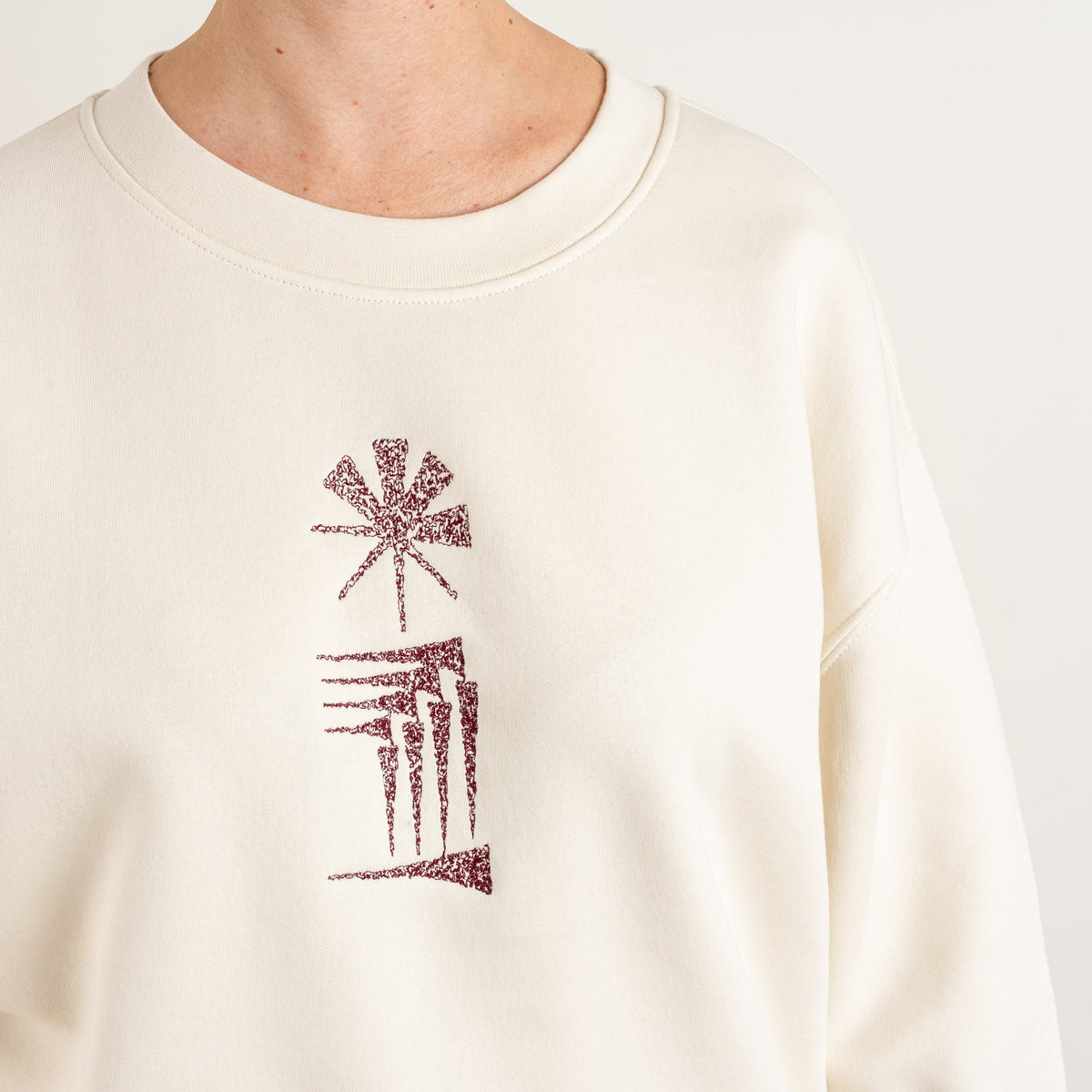 Close-up of the Star and House chest embroidery on the ecru sweatshirt
