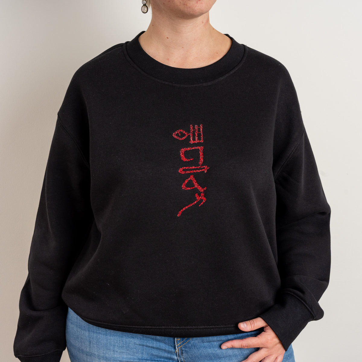 Detail view of the red Papyrus chest embroidery on the black sweatshirt
