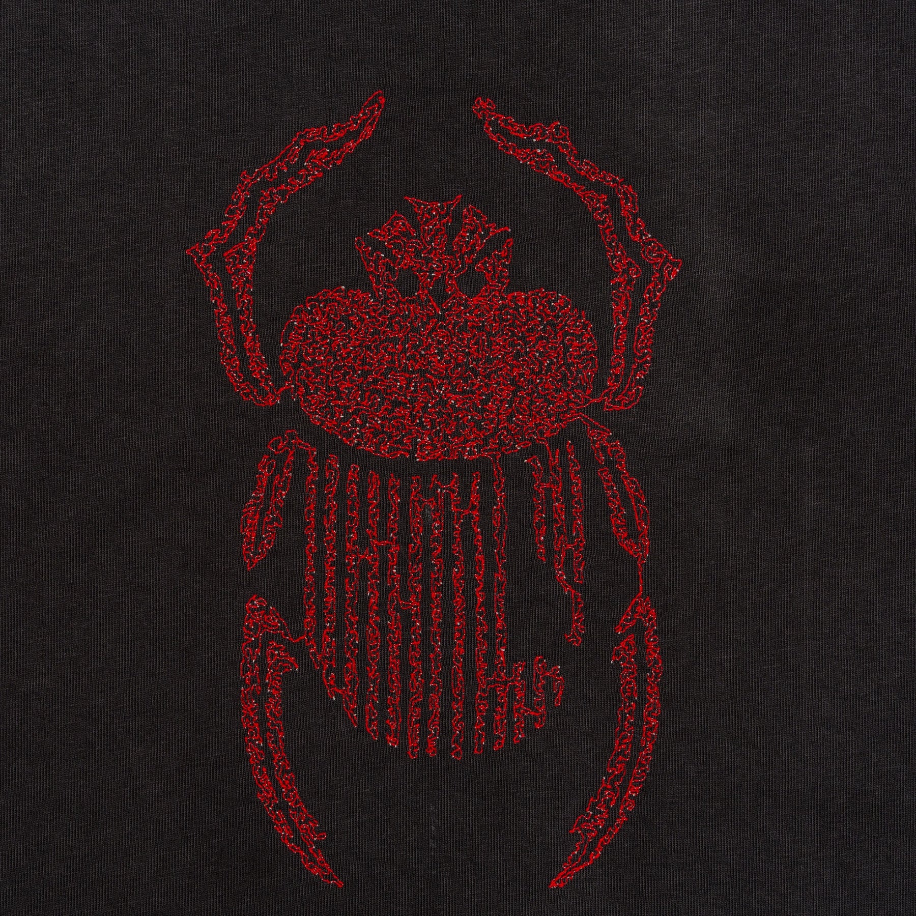 Close-up of red scarab embroidery stitched on the black Gordina Scarab T-shirt.