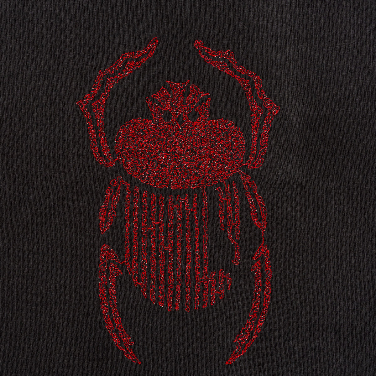 Close-up of red scarab embroidery stitched on the black Gordina Scarab T-shirt.