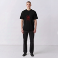 Load image into Gallery viewer, Front view of a model wearing the black Gordina Scarab T-shirt with centered red embroidery.
