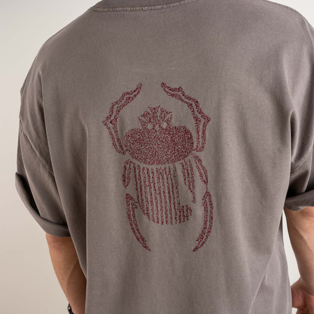 Detailed view of burgundy scarab stitching on the back of the Gordina faded grey T-shirt.