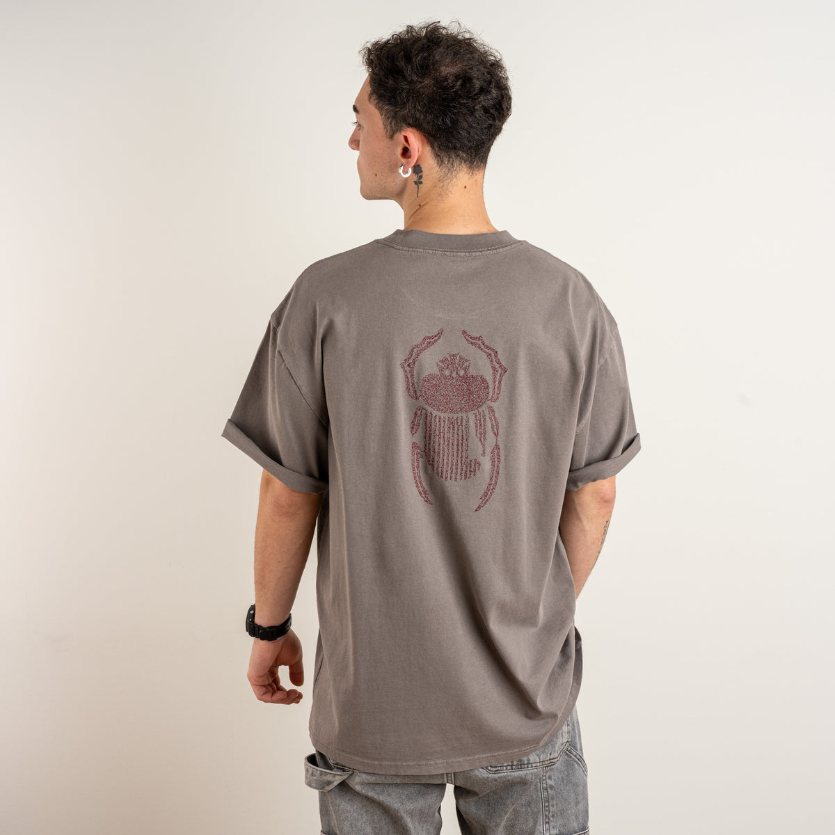 Three-quarter back view showing burgundy scarab embroidery on the faded grey Gordina T-shirt.