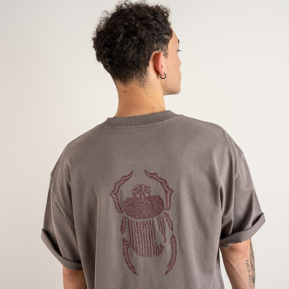 Close-up of the burgundy scarab embroidery on the faded grey Gordina heavyweight cotton T-shirt.