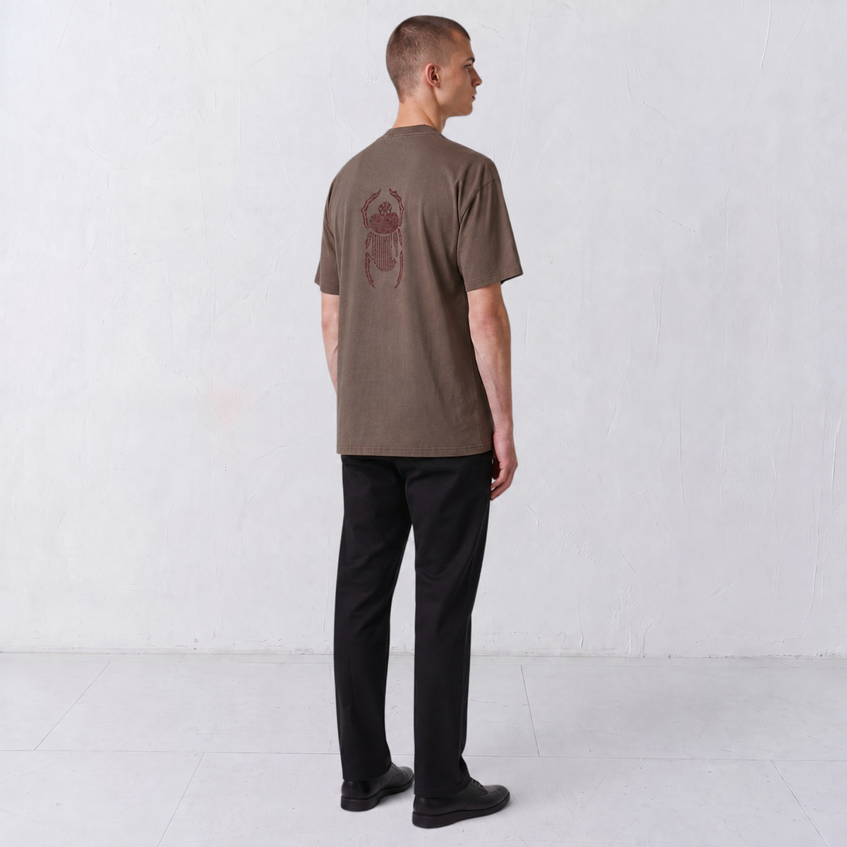 Three-quarter back view of the Gordina The Scarab grey T-shirt with burgundy embroidery.