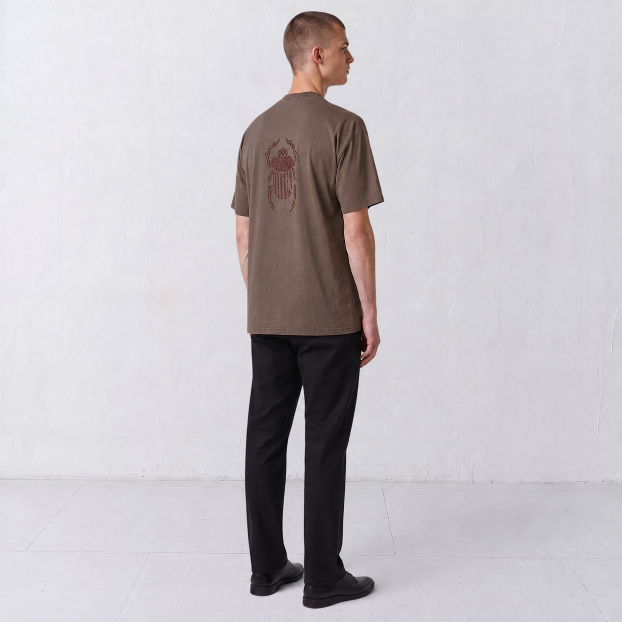 Three-quarter back view of the Gordina The Scarab grey T-shirt with burgundy embroidery.