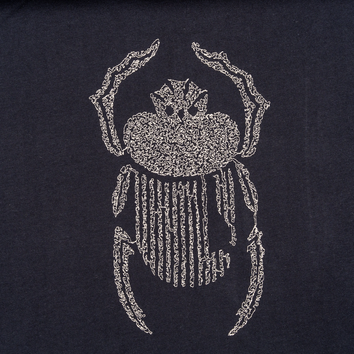 Close-up of ivory scarab embroidery on the Gordina navy oversized cotton T-shirt.