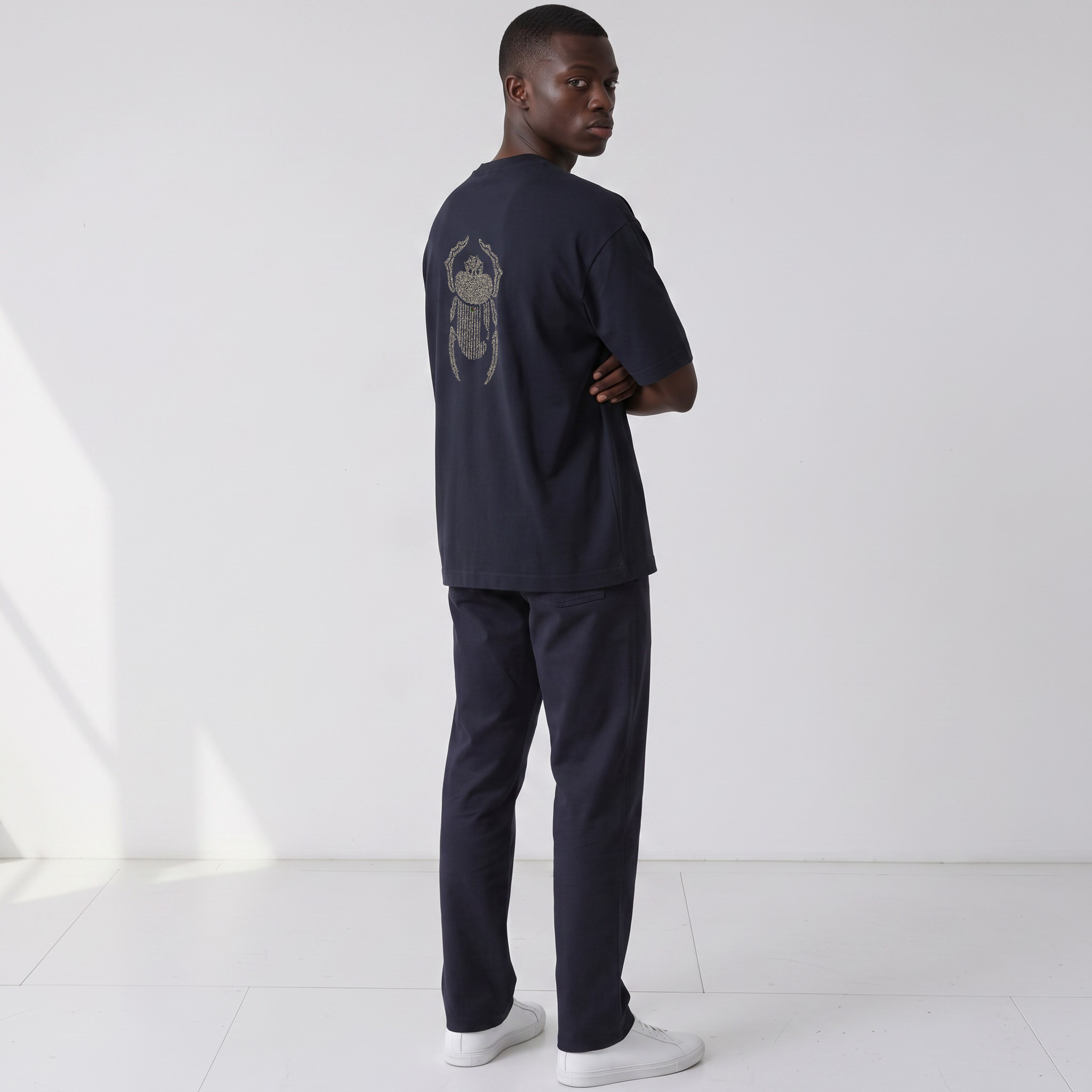 Three-quarter back view of the Gordina The Scarab navy oversized T-shirt with ivory embroidery.