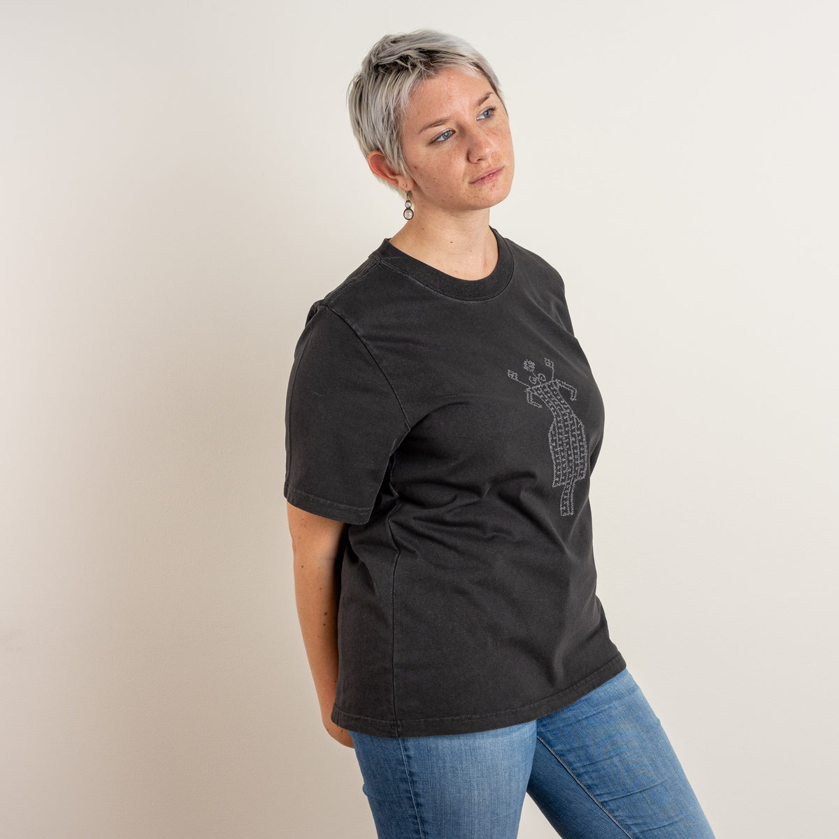 Side view of a model wearing The Ward women’s Faded Coal T-shirt with subtle grey embroidery on the front.