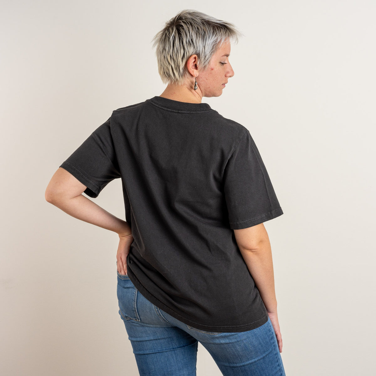 Three-quarter back view of a model wearing The Ward women’s Faded Coal T-shirt, showing the plain back and relaxed fit.