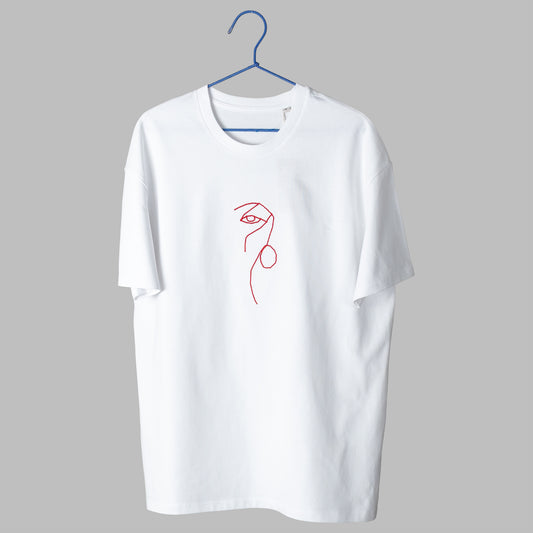 A white t-shirt on a blue wire hanger against a light grey background. It features a small, abstract embroidered design on the center chest consisting of a continuous, minimalist red line that forms the shape of an eye and nose profile.