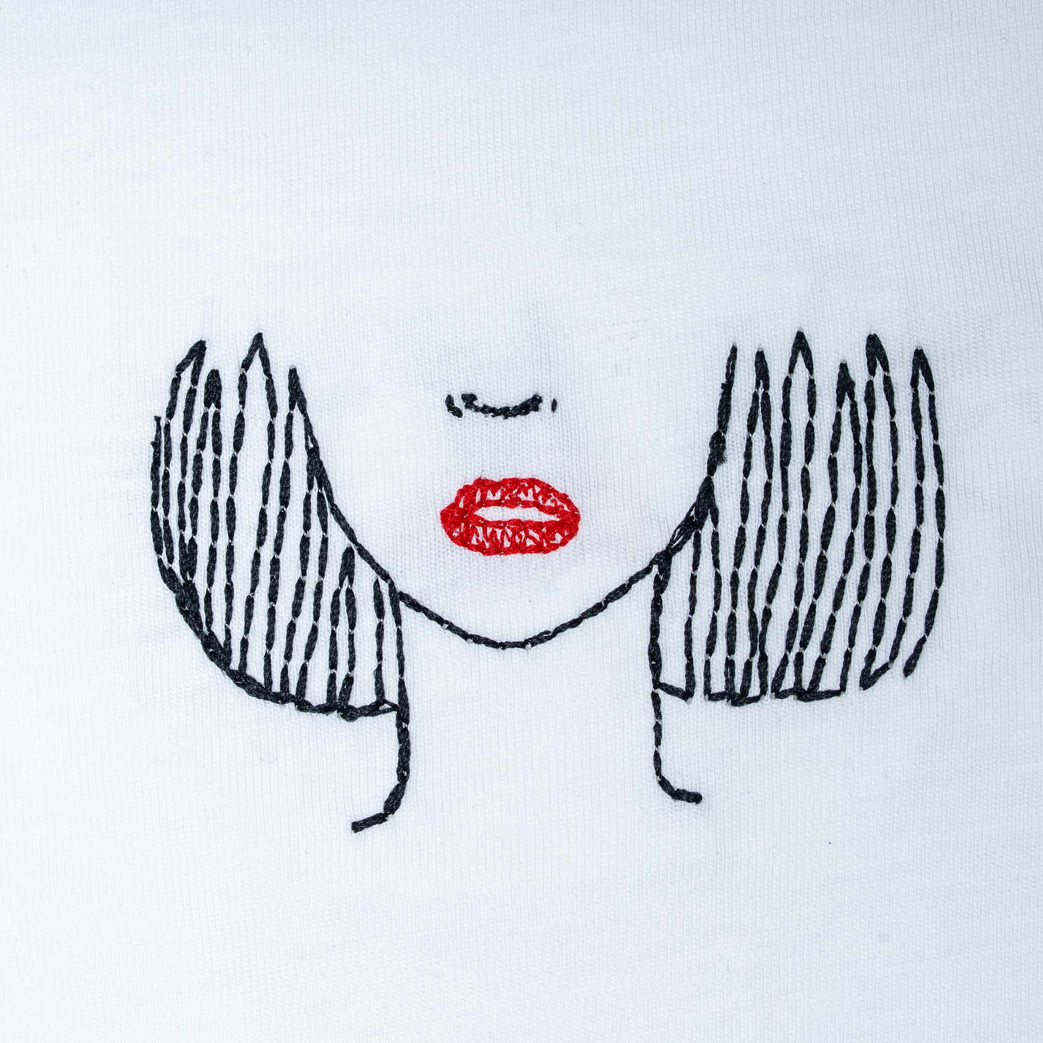 Close-up of white organic cotton t-shirt with minimalist face embroidery and red lips detail, Gordina