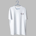Load image into Gallery viewer, A white t-shirt on a blue wire hanger against a light grey background. It features a small embroidered design on the left chest showing the lower half of a face, including a nose, bright red lips, and a black line-art bob haircut.
