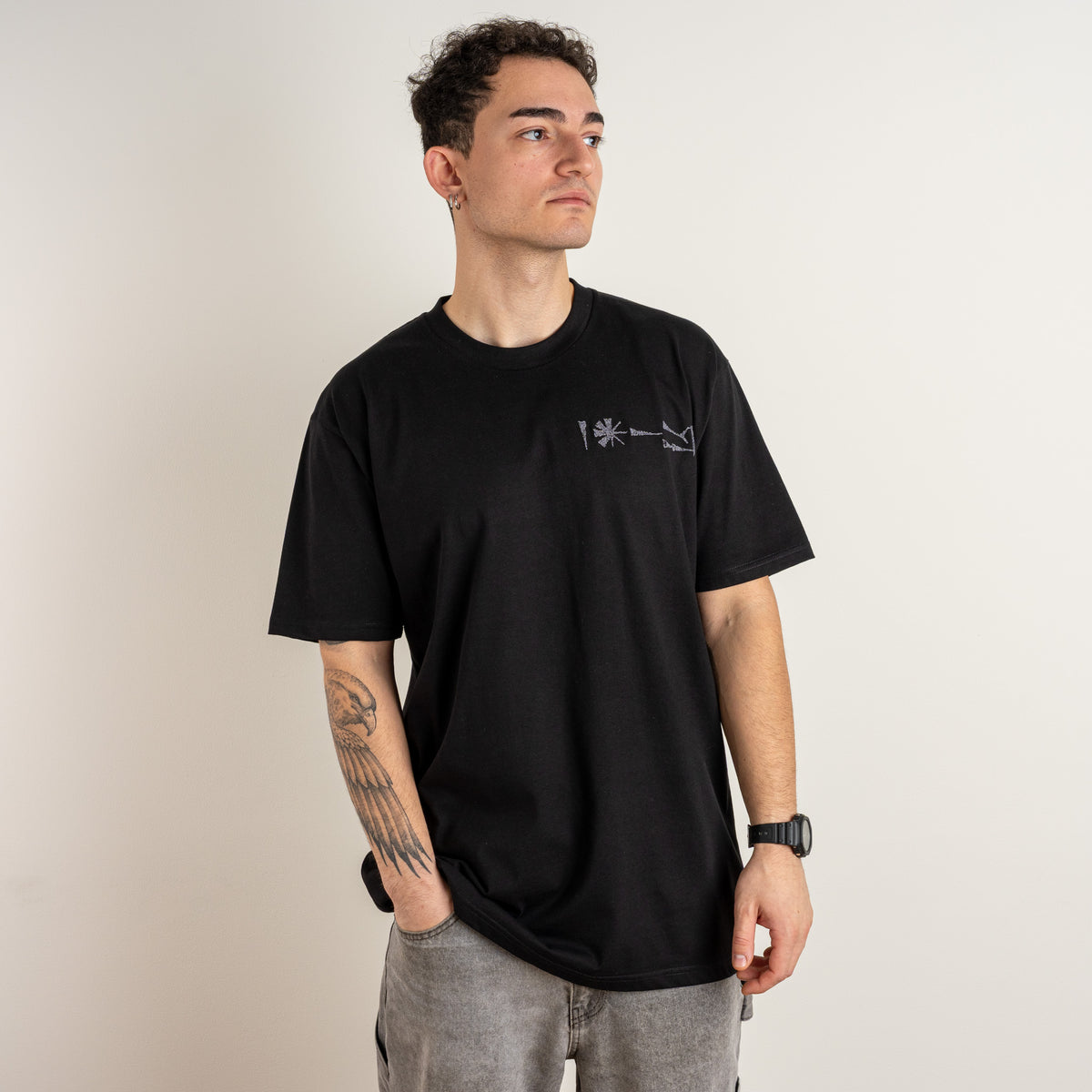 Three-quarter view of the Undeciphered black cotton T-shirt with pale chest embroidery by Gordina.