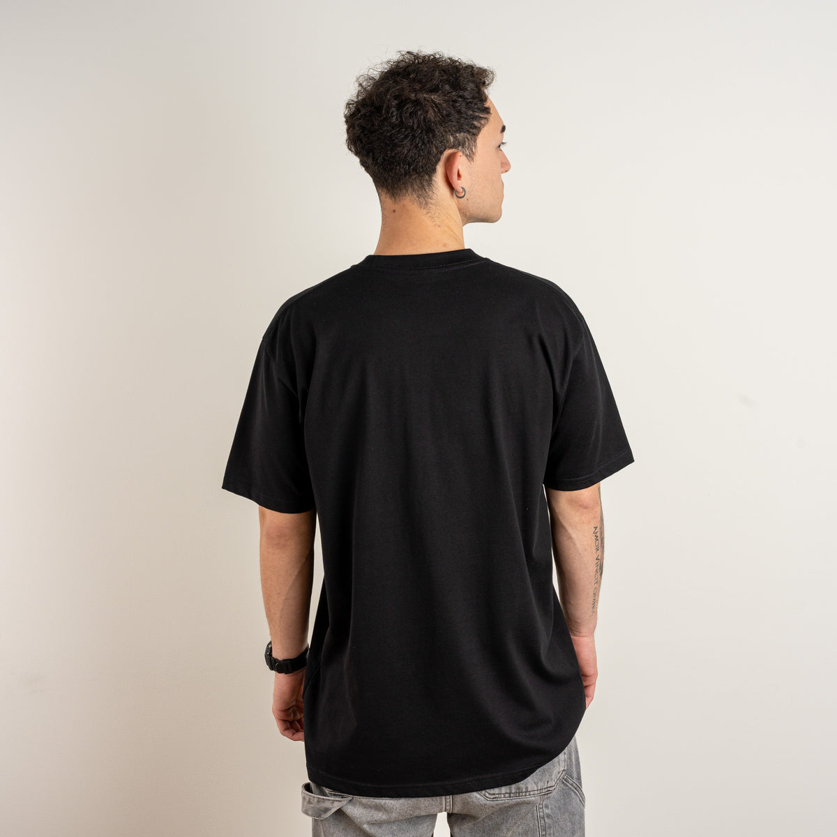 Close-up of the cuneiform-inspired embroidered sign on the chest of the black Undeciphered T-shirt.