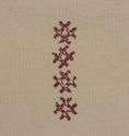 Load image into Gallery viewer, Close-up of the vertical burgundy cross-stitch motif on the beige Gordina Unsigned T-shirt.
