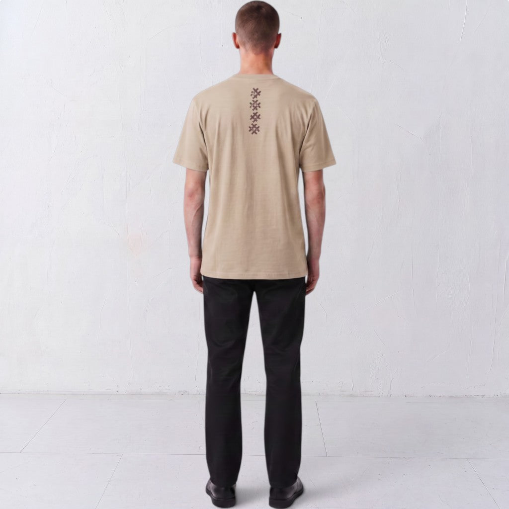 Back view of a model wearing the beige Gordina Unsigned T-shirt with vertical burgundy embroidery.