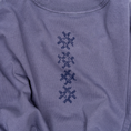Load image into Gallery viewer, Angled detail of navy cross embroidery stitched on faded indigo cotton for the Gordina Unsigned T-shirt.
