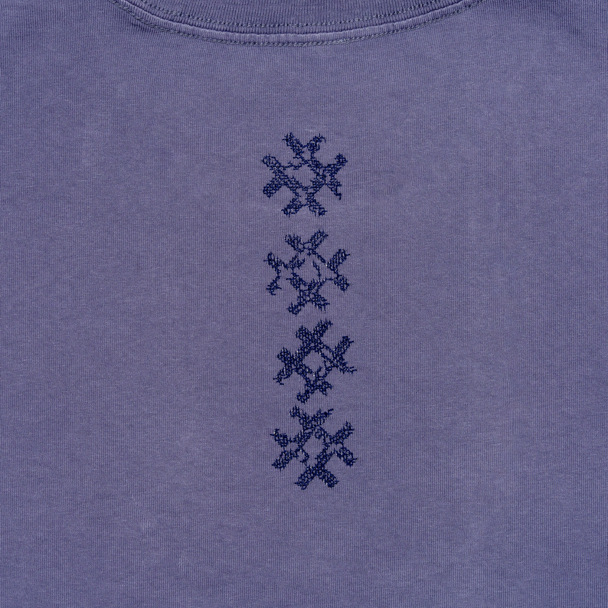 Close-up of vertical navy cross embroidery on the Gordina Unsigned faded indigo cotton T-shirt.