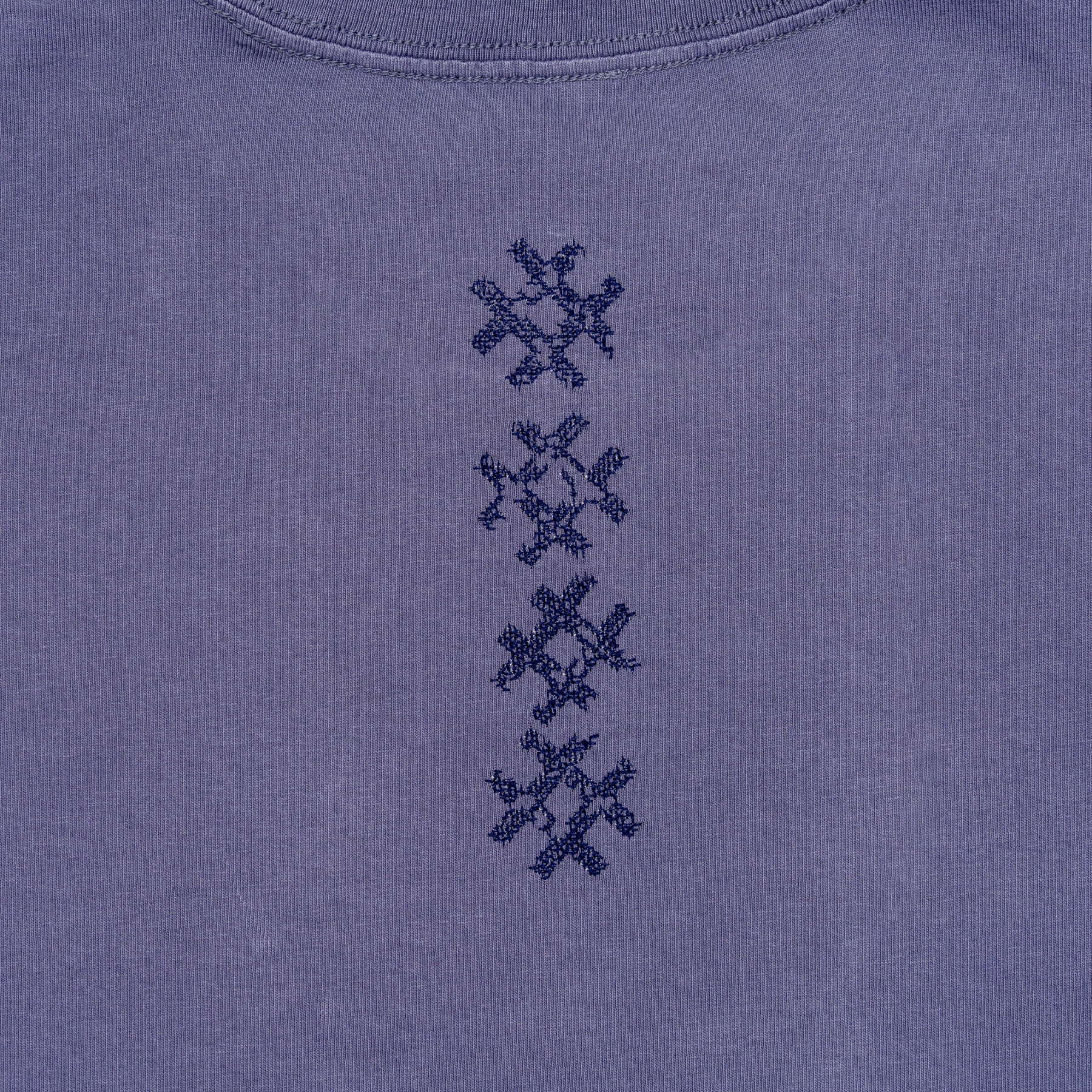Close-up of vertical navy cross embroidery on the Gordina Unsigned faded indigo cotton T-shirt.
