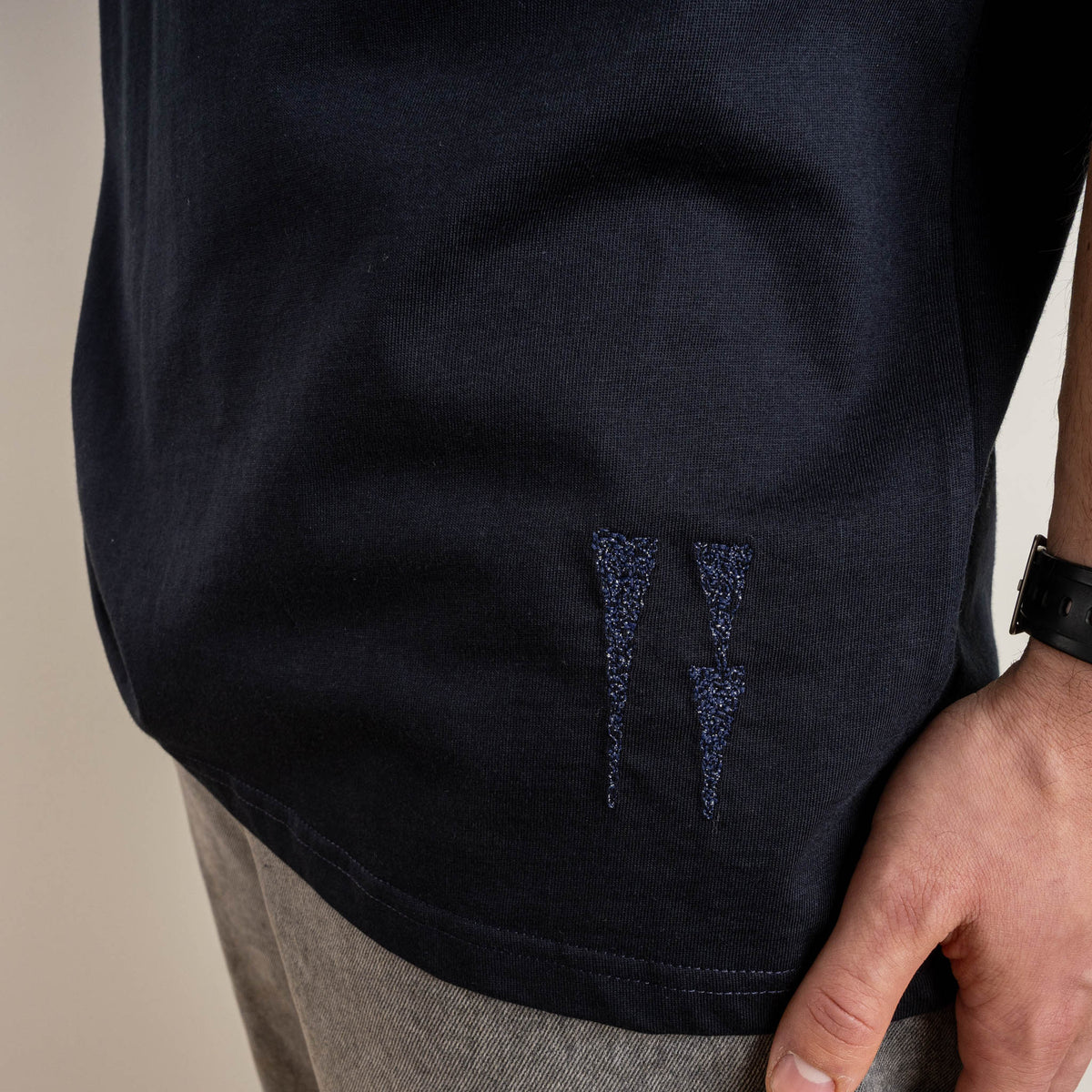 Detail of the embroidered water signs near the hem on the navy Water and the Star T-shirt.